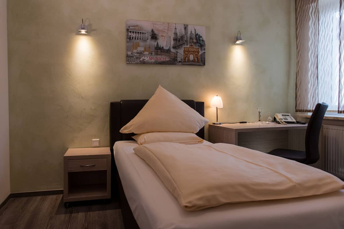 Une chambre d’hôtel avec un lit, des tables de chevet, un bureau et une lampe.