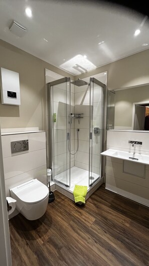 A modern bathroom with a glass-enclosed shower, a toilet, and a sink. - Ziegenbruch's Hotel & Restaurant (Spenge)