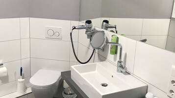 A modern bathroom with a toilet, sink, and mirror.