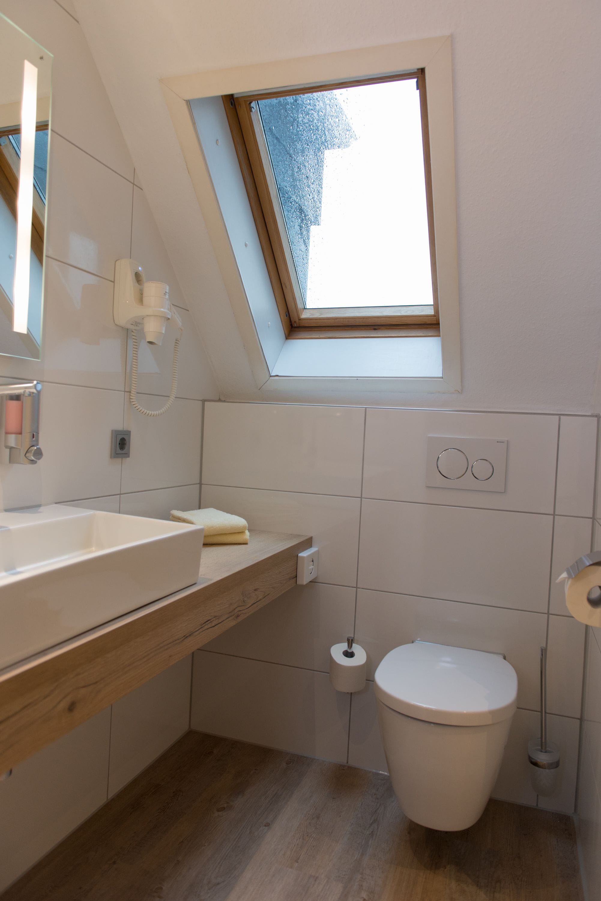 Ein kleines, modernes Badezimmer mit Oberlicht, Toilette und Waschbecken.