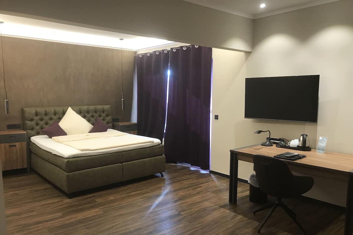 Une chambre d’hôtel moderne équipée d’un lit, d’un bureau et d’une télévision.