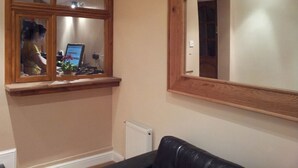 A room with a window, a radiator, and a black leather sofa. - Dharma Lodge (Enfield)
