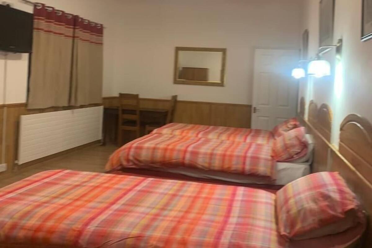 Um quarto pequeno e aconchegante com duas camas, uma escrivaninha e uma cadeira.