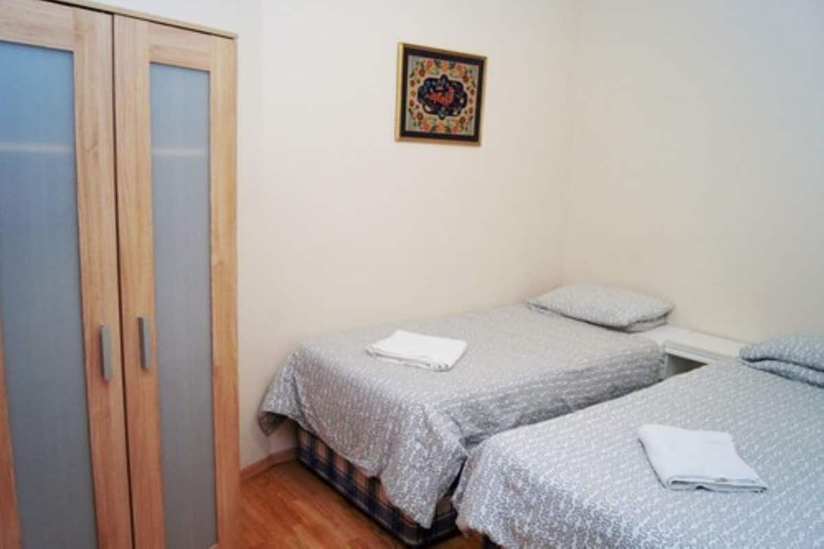 Quarto com duas camas de solteiro, um guarda-roupa e um quadro na parede.