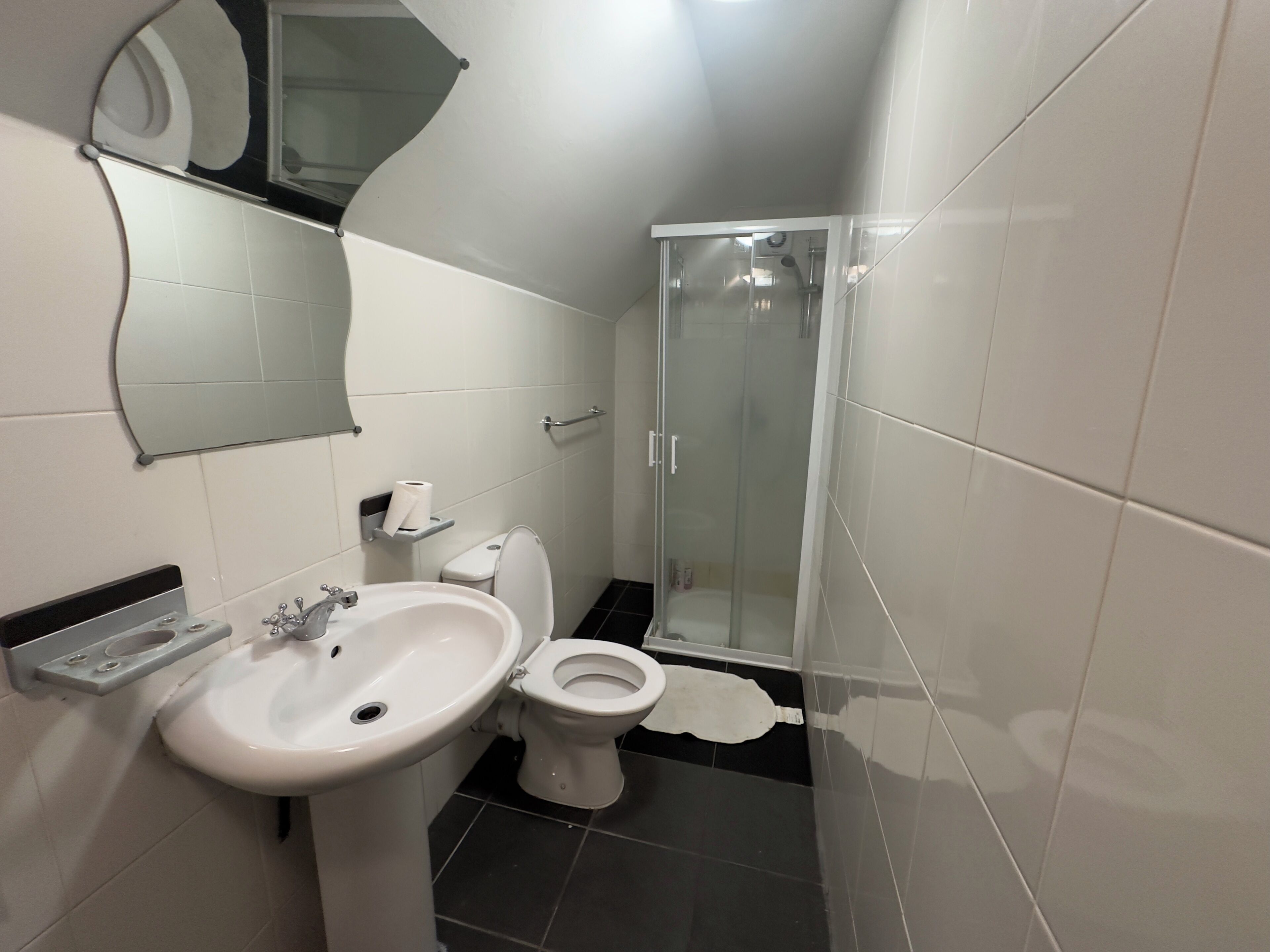 A bathroom with a sink, toilet, and glass shower enclosure.