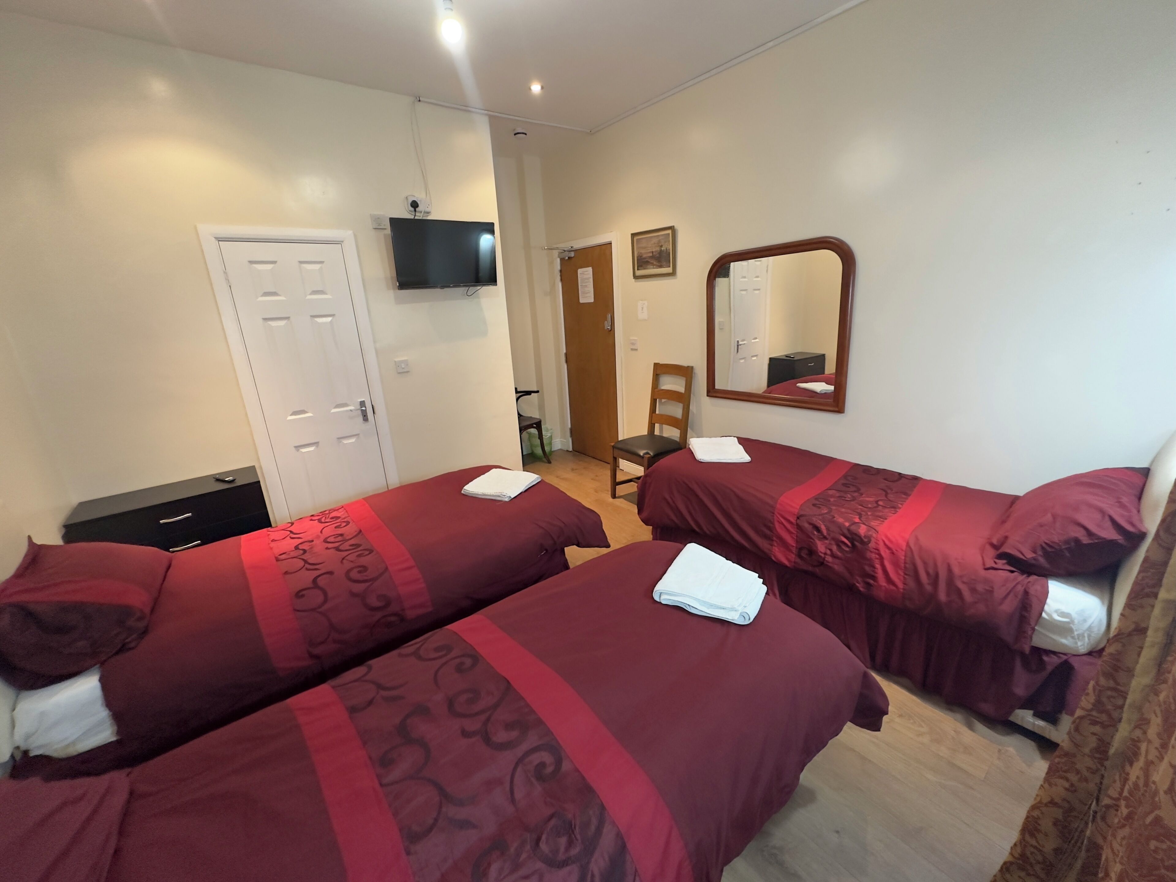 Une chambre d’hôtel avec deux lits, une télévision, un miroir et une porte.