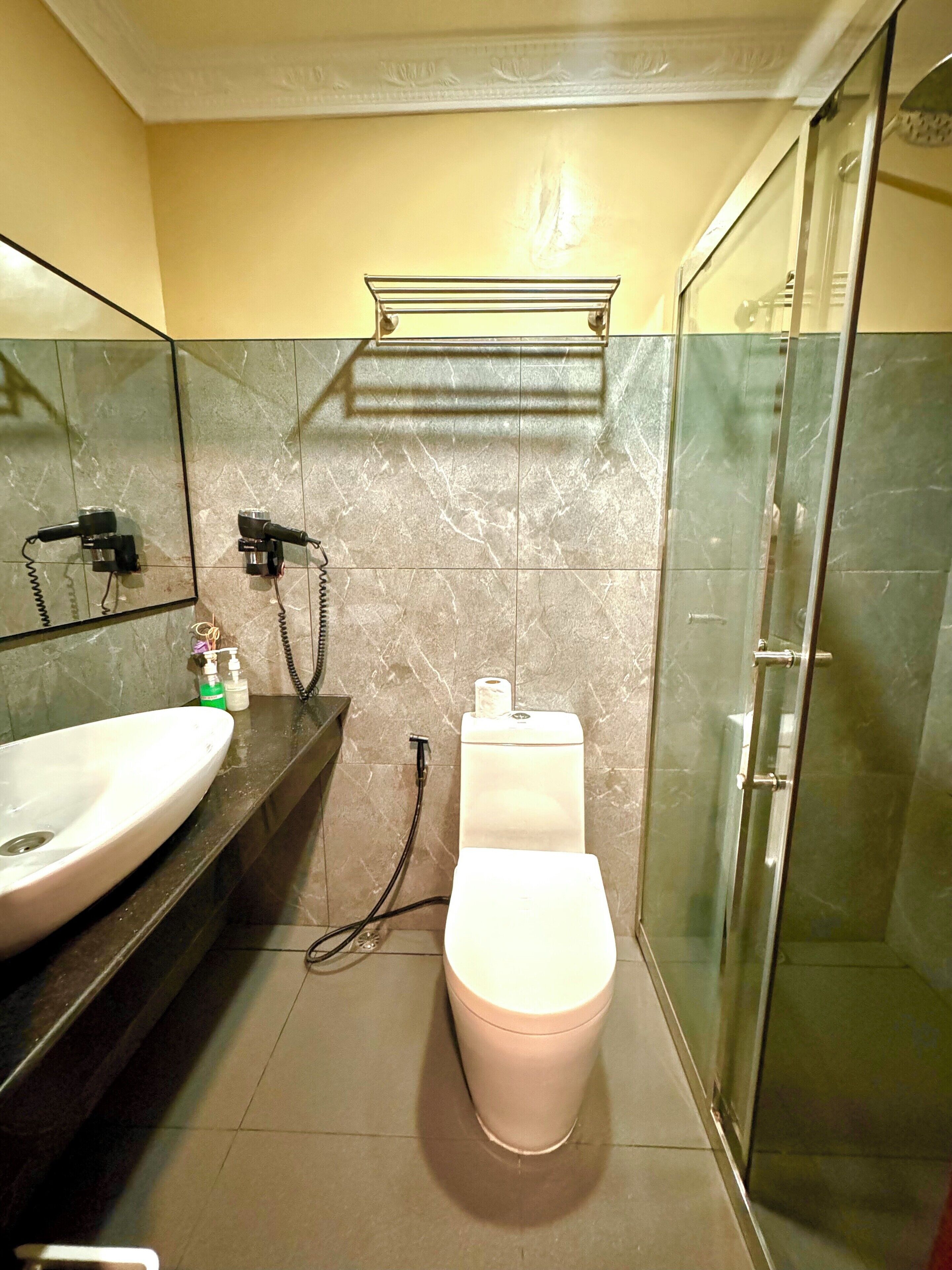 Ein Badezimmer mit einem weißen Waschbecken, einer Toilette und einer Duschkabine aus Glas.