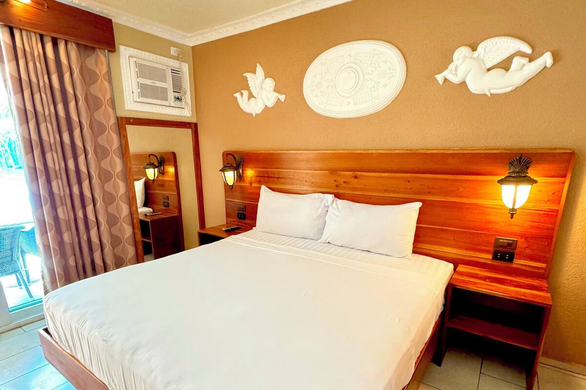A large bed with a wooden headboard, two bedside tables with lamps, and decorative wall art.