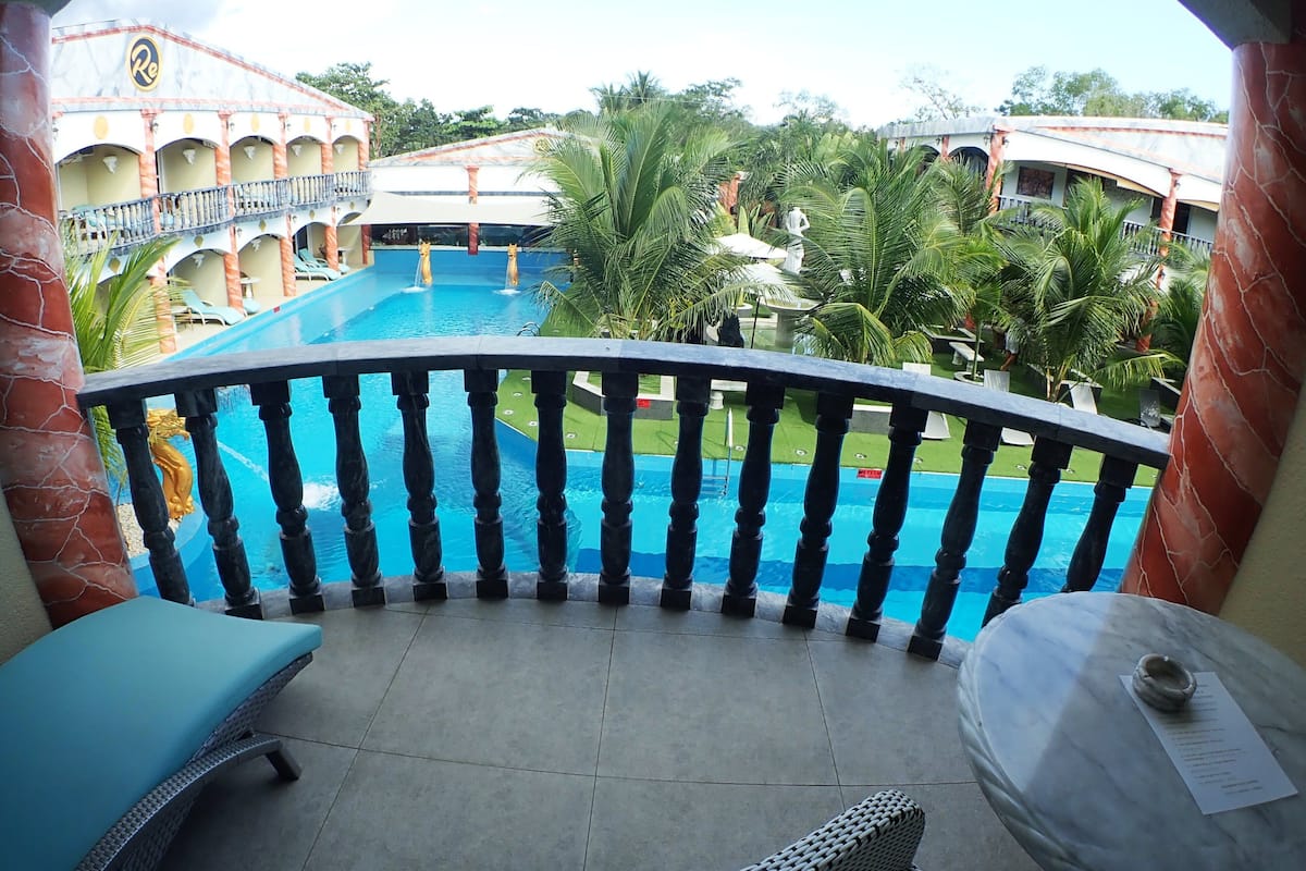 A balcony with a view of a swimming pool, lounge chairs, and a table with a menu.