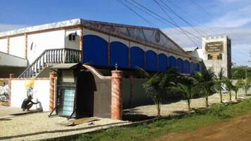 Un edificio con fachada azul, una escalera y una torre con reloj.