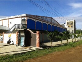 Un edificio con fachada azul, una escalera y una torre con reloj.