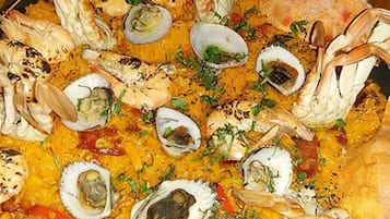 A seafood paella with various shellfish and shrimp, garnished with herbs, served on a large platter.