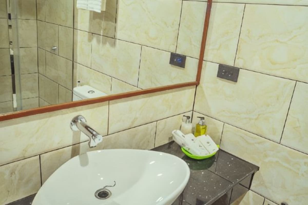 A bathroom with a sink, mirror, and toiletries.