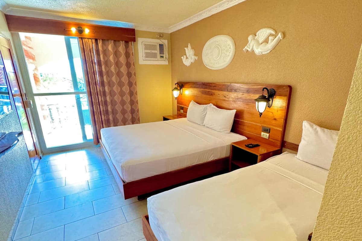 A hotel room with two beds, a wooden headboard, a wall-mounted light, and a decorative plate.