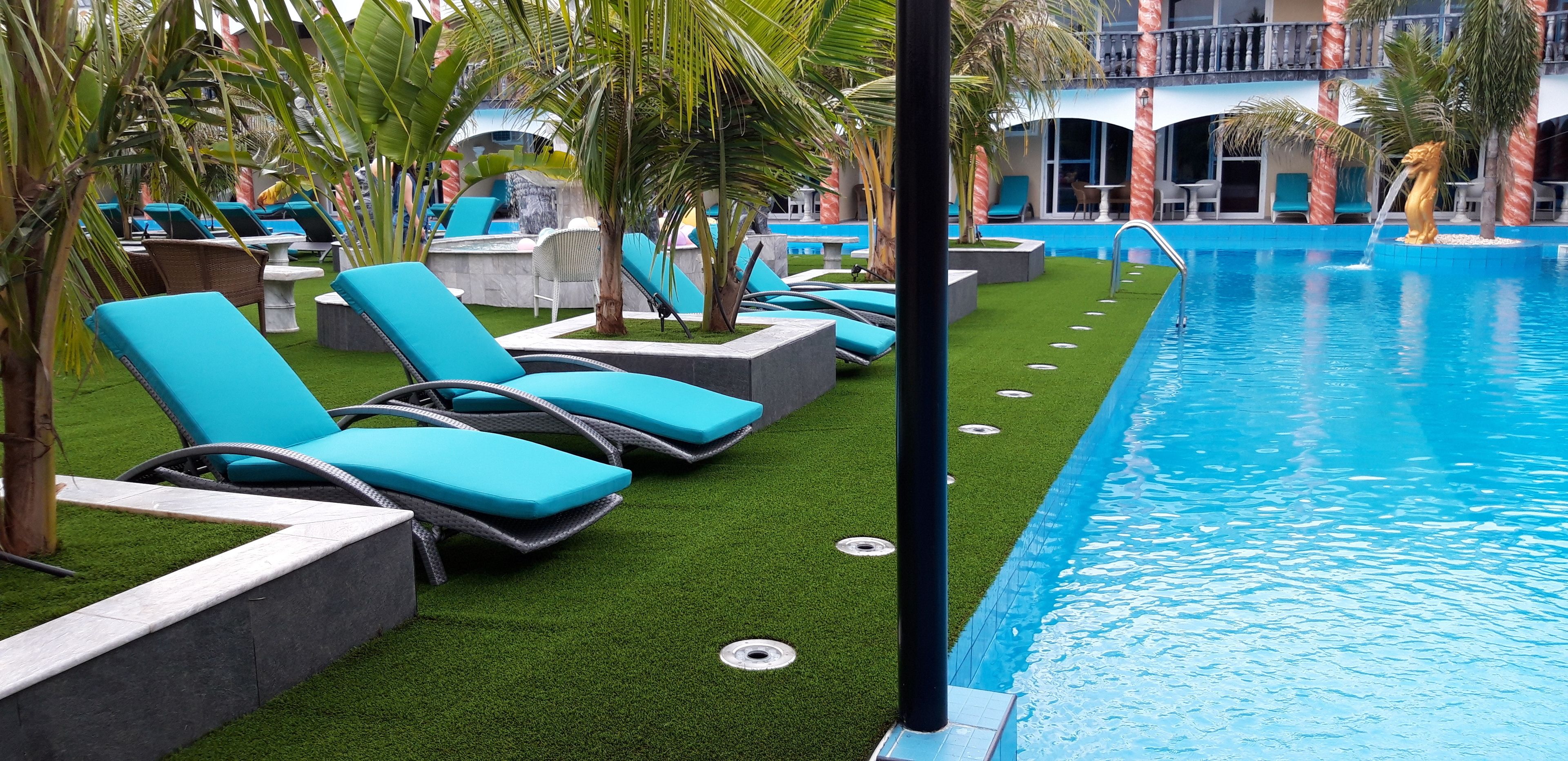 A poolside area with blue lounge chairs, a small pool, and palm trees.