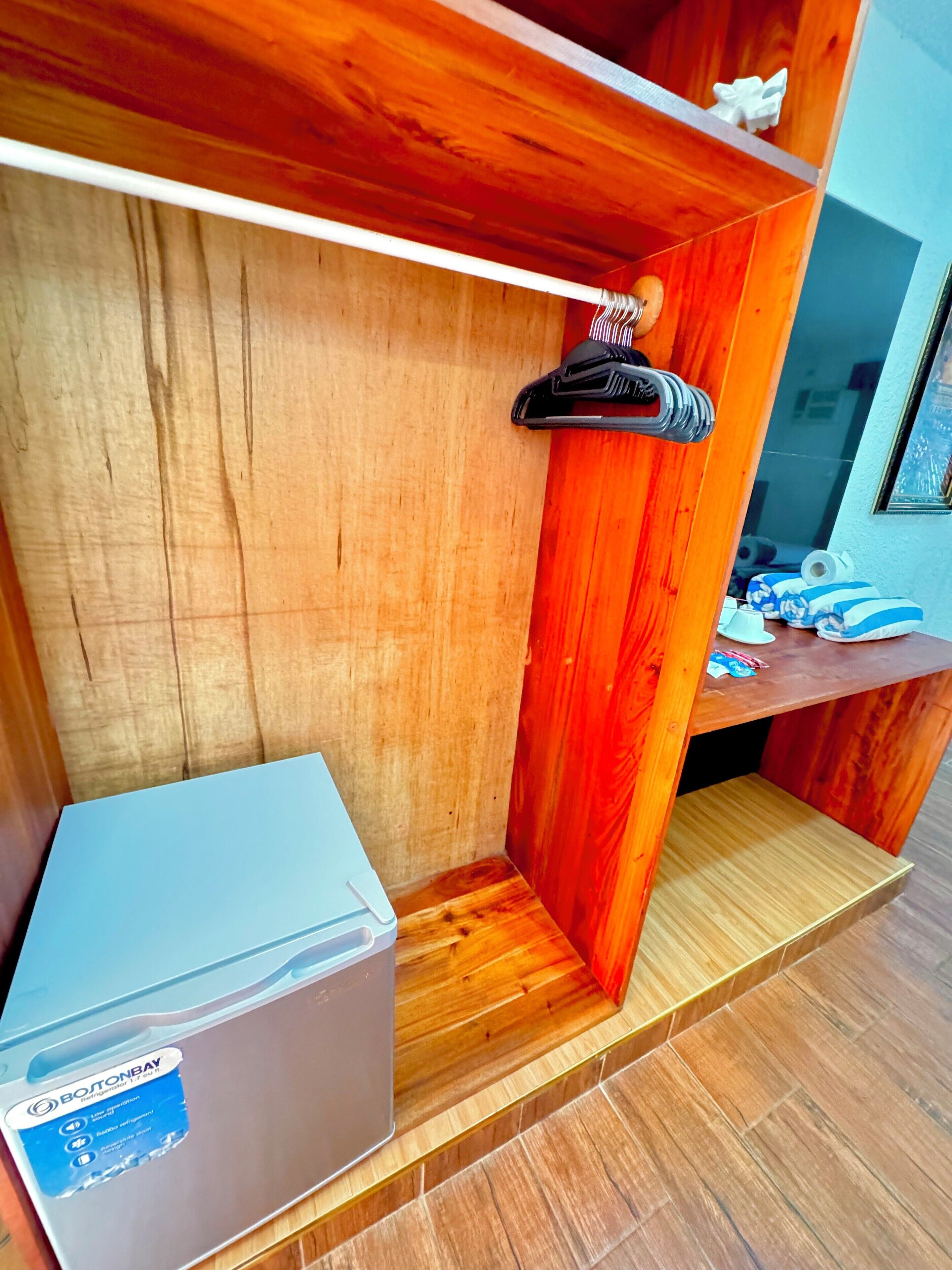 A wooden storage unit with a hanging rack, a small shelf, and a box on the floor.