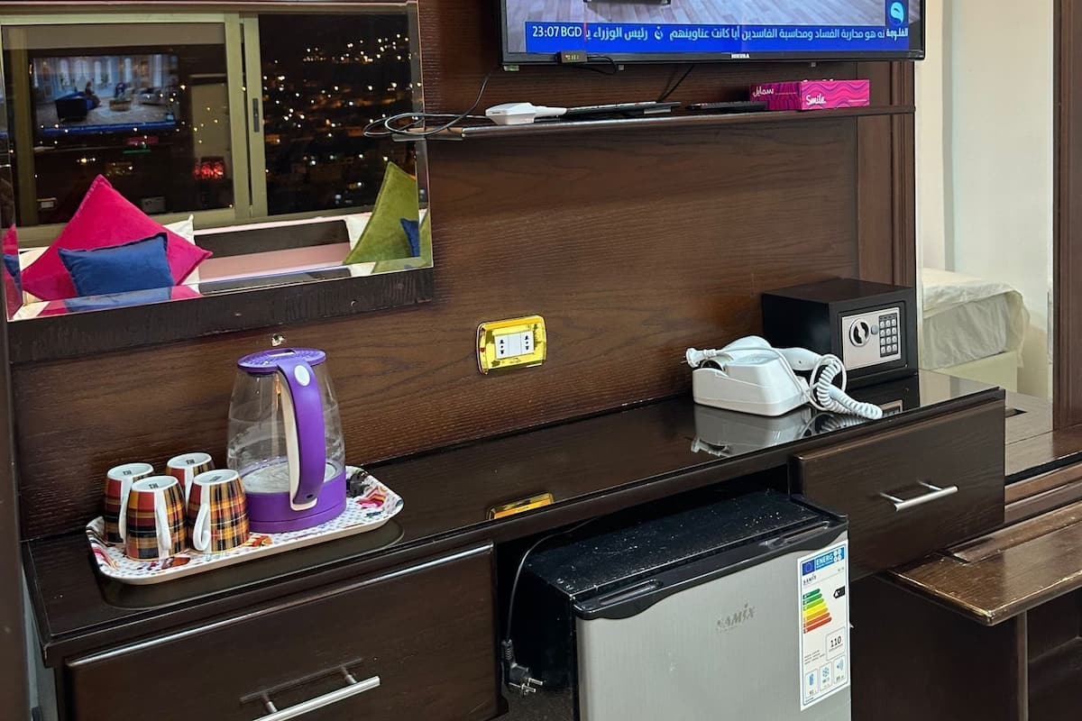 A hotel room with a television mounted on the wall, a minibar, a coffee maker, and a refrigerator.