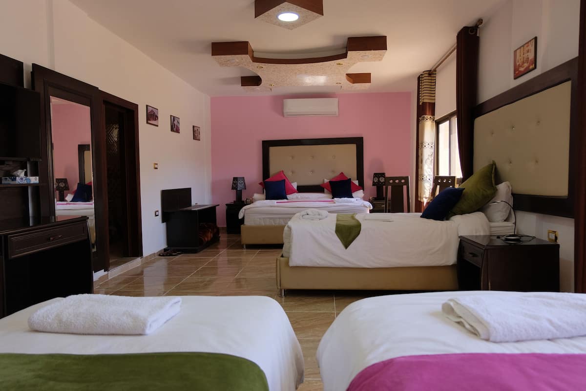 A hotel room with two beds, a large mirror, a wardrobe, and a ceiling with a unique design.