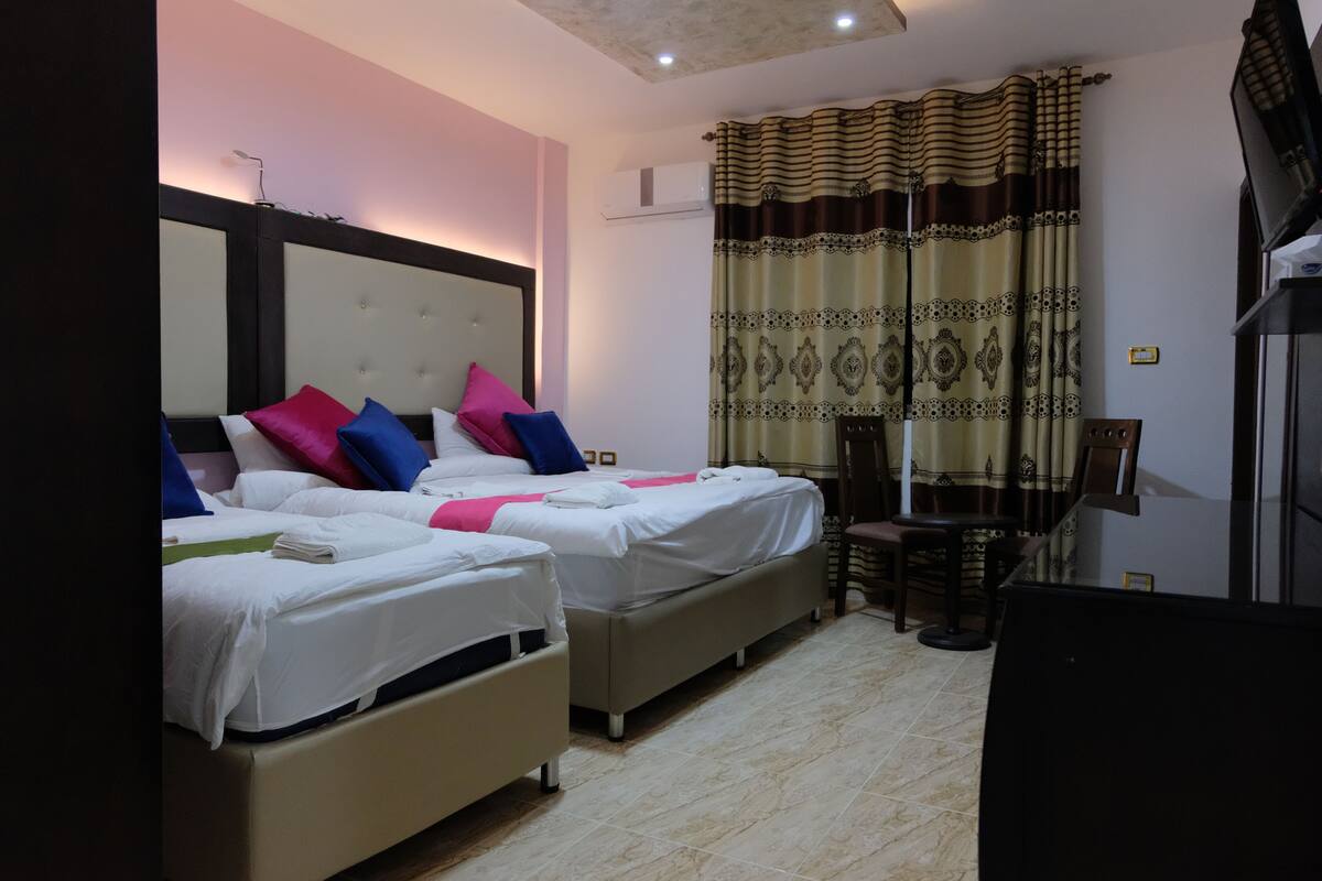 A hotel room with two beds, a desk, and a chair.
