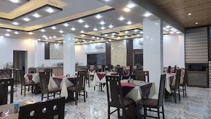 Ein Restaurant mit mehreren Tischen und Stühlen, Marmorboden und modernen Leuchten.