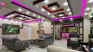 Eine geräumige Lobby mit einer Rezeption, Sofas und einem großen Flachbildfernseher.