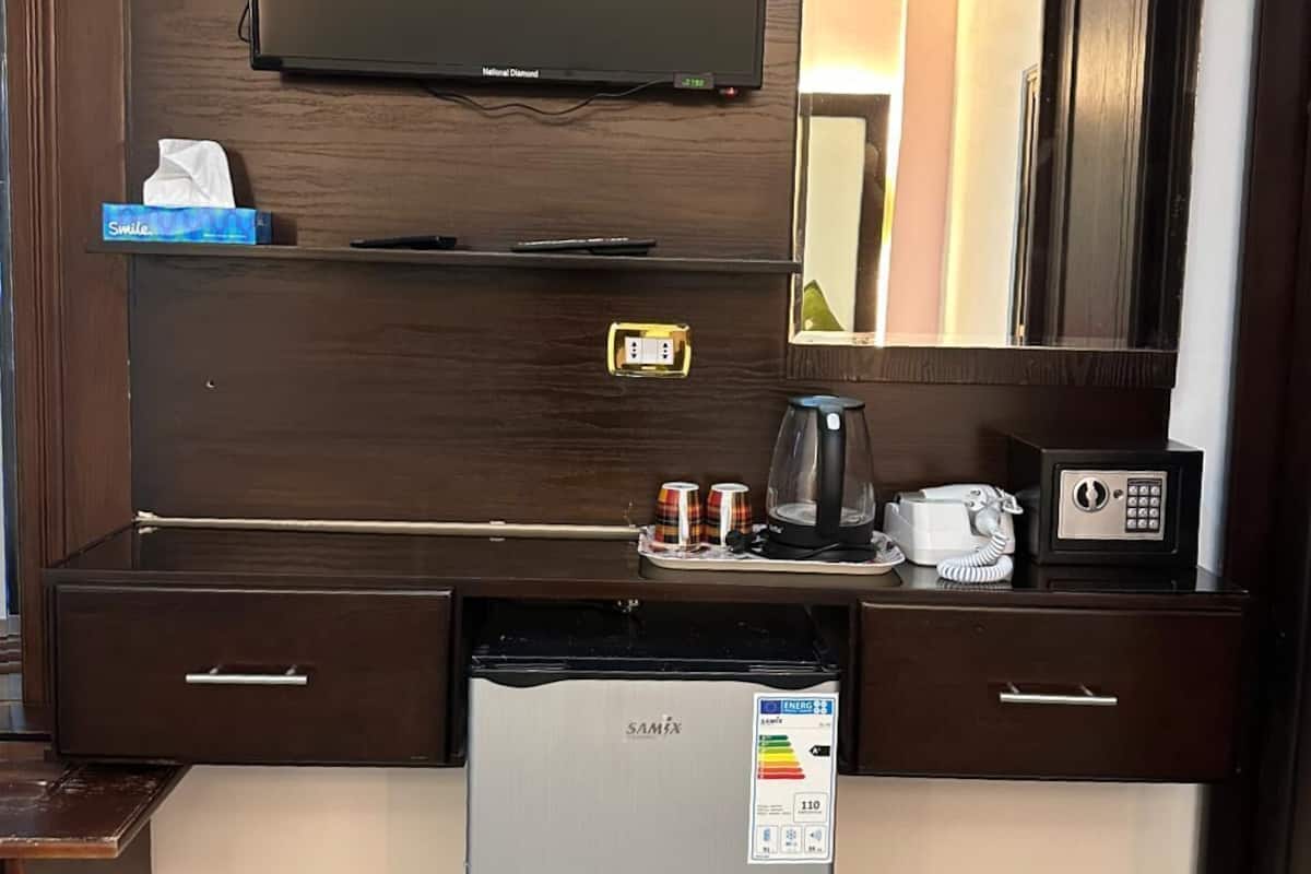 A compact kitchenette with a built-in refrigerator, a microwave, a coffee maker, and a telephone.