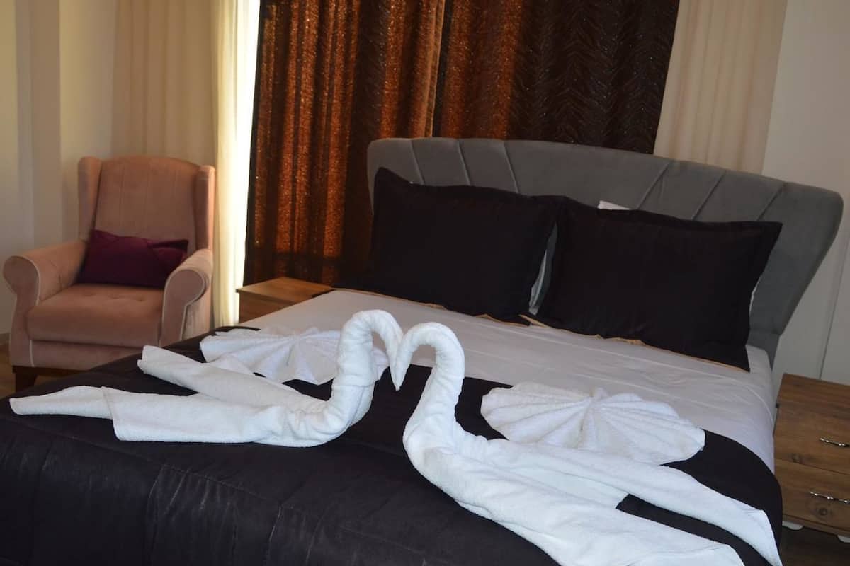 A hotel room with a bed, a chair, and curtains.