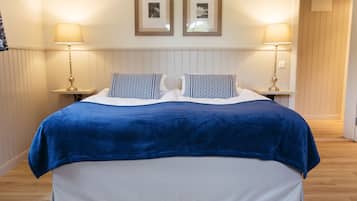 A neatly made bed with a blue blanket, two bedside lamps, and a headboard with framed pictures.