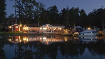 Enjoy waterfront dining and tranquil views from this property's outdoor area, situated beside a calm body of water.