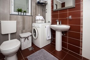 A modern bathroom with a toilet, washing machine, and sink. - Apartments Toni Relax (Split)