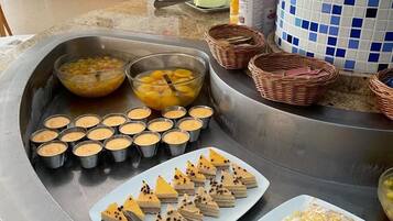 A buffet with various dishes including custard cups, a plate of layered desserts, and a dish with shredded cheese and meat.