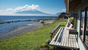 A wooden deck with a view of a beach and a mountain.