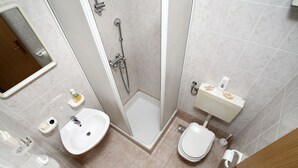 A modern bathroom with a shower, toilet, sink, and mirror. - Apartments Adriatic (Podstrana)