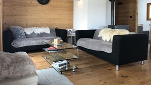 A modern living room with two sofas, a glass coffee table, a clock, and a fireplace. - Chalet - La Tzoumaz (La Tzoumaz)
