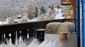 A wooden deck with a view of snow-covered mountains, a black mug with 'Guinness' on it, and a fluffy white pillow. - Chalet - La Tzoumaz (La Tzoumaz)
