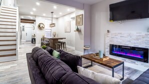 A modern living room with a dark-colored sofa, a wooden coffee table, and a flat-screen TV mounted on the wall.