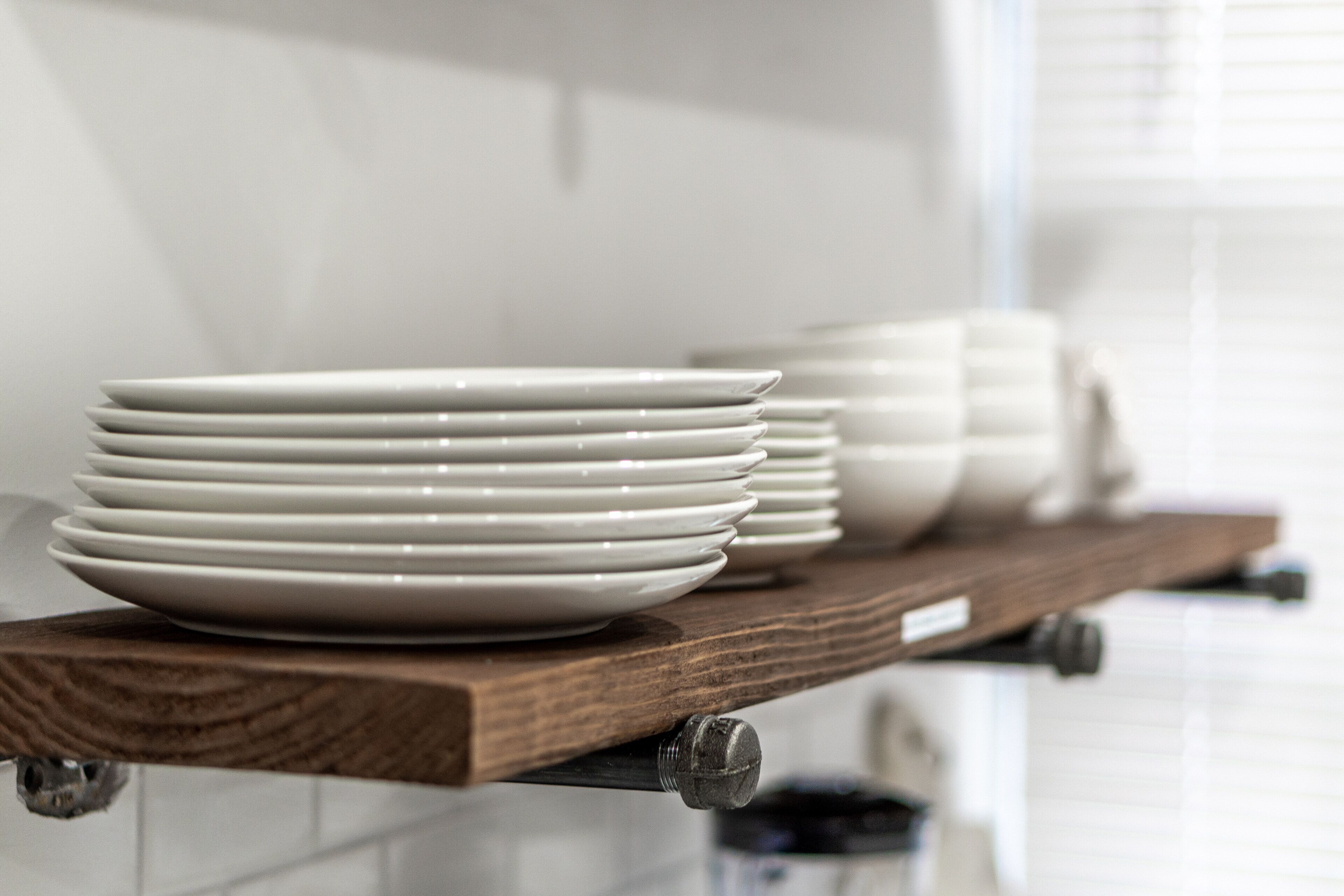 Une étagère de cuisine avec des assiettes blanches empilées.