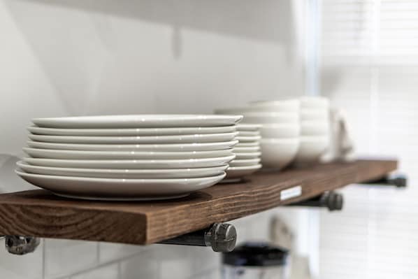Una estantería en la cocina con platos blancos apilados.