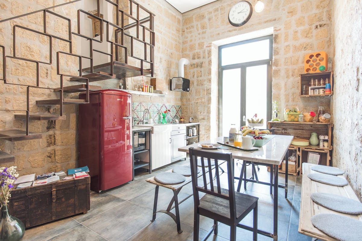 A kitchen with a red refrigerator, a wooden cabinet, and a dining area with stools.