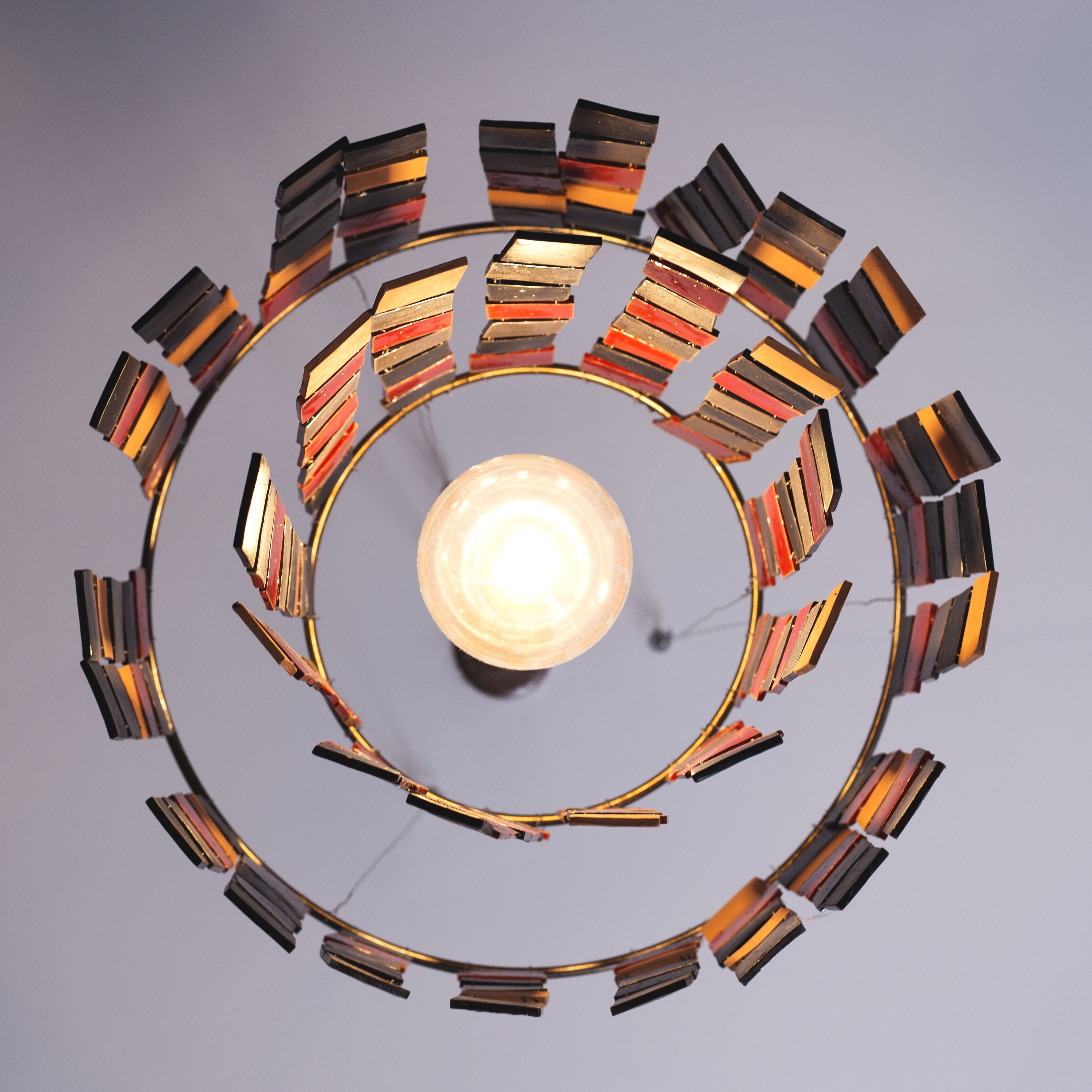 A circular chandelier with multiple tiers of metallic and wooden elements.