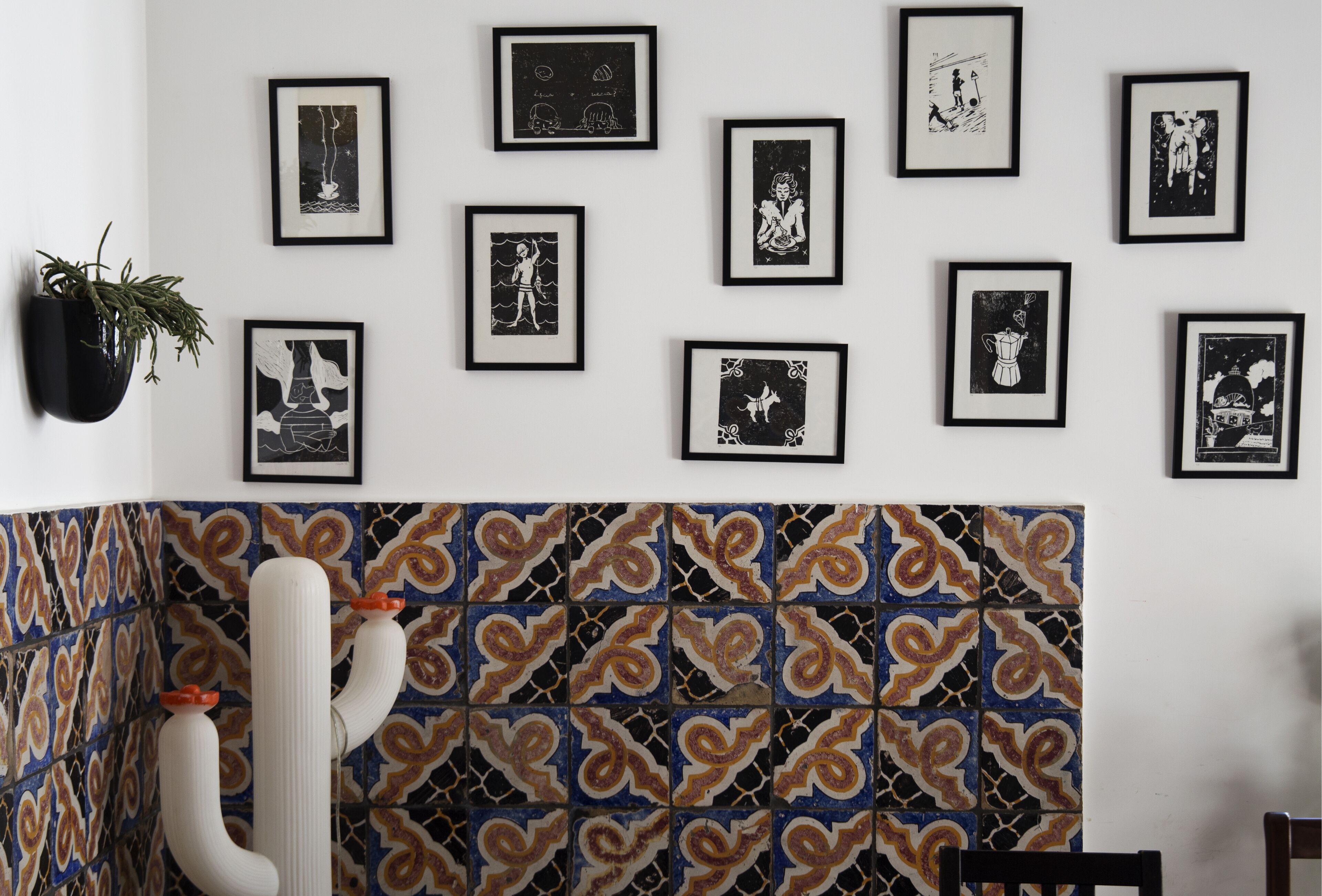 A room with a tiled backsplash, a white chair, and a black planter with a plant.