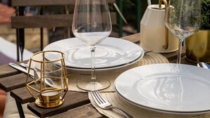 A table set for two with plates, wine glasses, and cutlery on a balcony overlooking a bridge. - Romantic Gem in Alcântara (Lisboa)