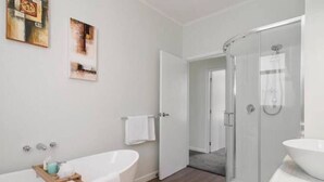 Un bagno moderno con una vasca freestanding, una doccia con pareti in vetro e un ampio specchio.