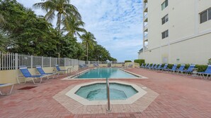 A swimming pool with blue lounge chairs and a white fence.