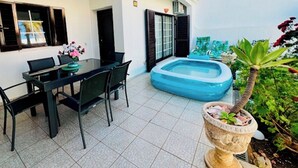 Un coin repas avec une table et des chaises, une petite piscine et une plante en pot.