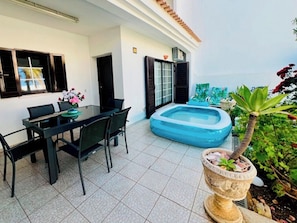 Un coin repas avec une table et des chaises, une petite piscine et une plante en pot.