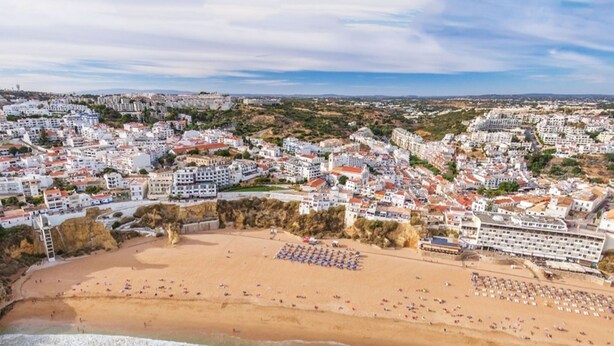 Vue aérienne d’une ville côtière avec une plage, des bâtiments blancs et un grand hôtel.