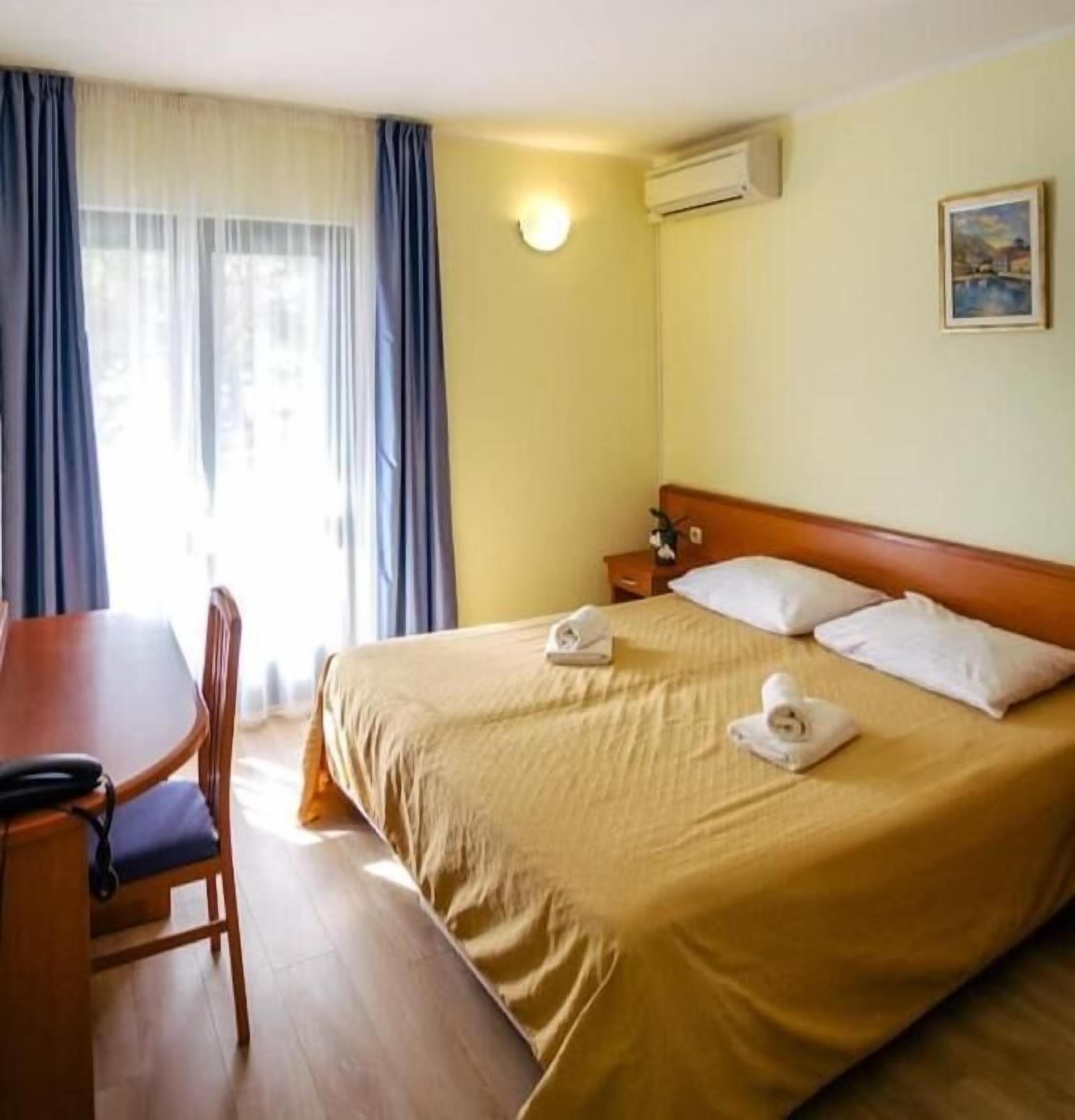 A hotel room with a bed, a desk, and a chair.