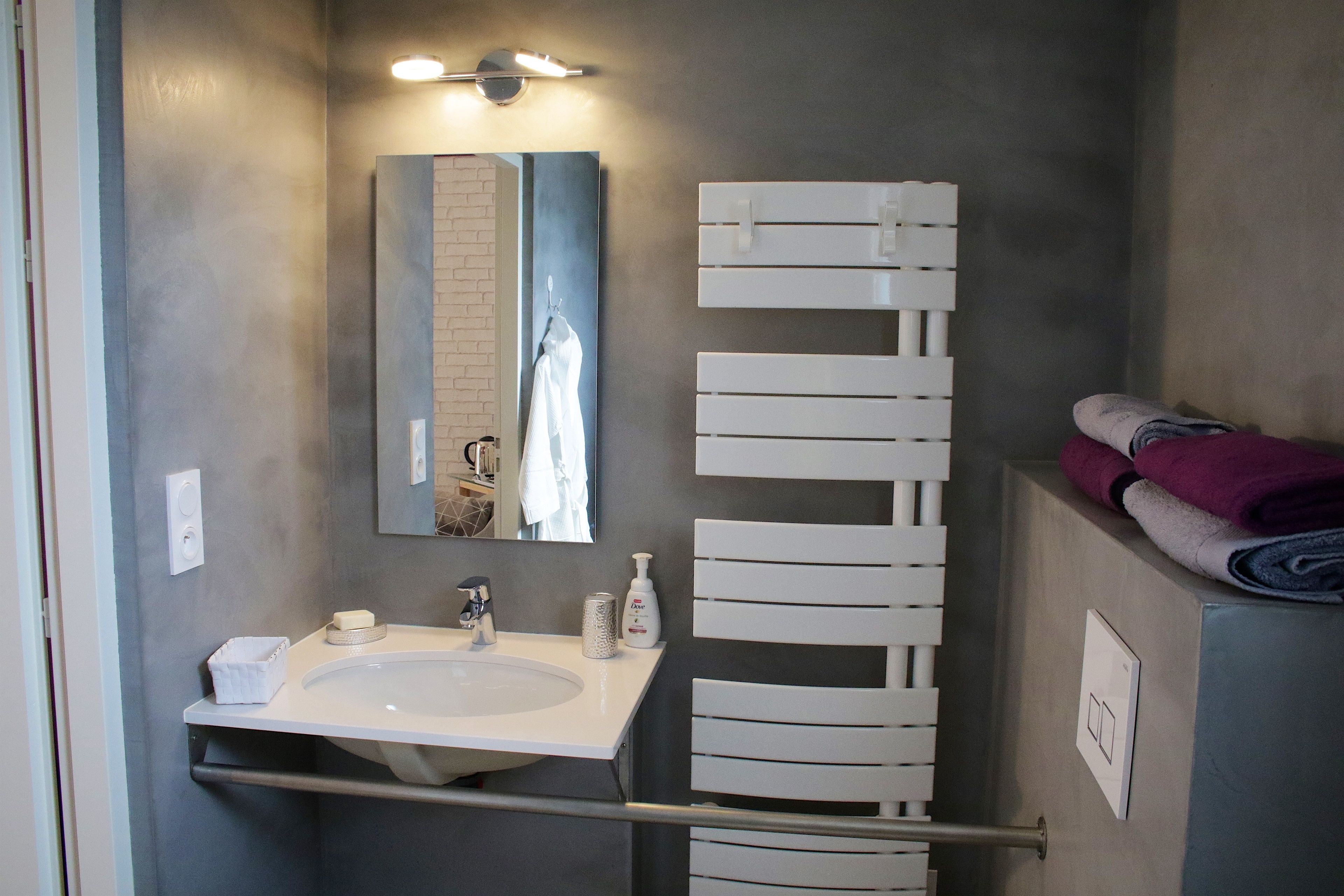 Ein modernes Badezimmer mit einem weißen Waschbecken, einem Spiegel und einem Handtuchhalter.