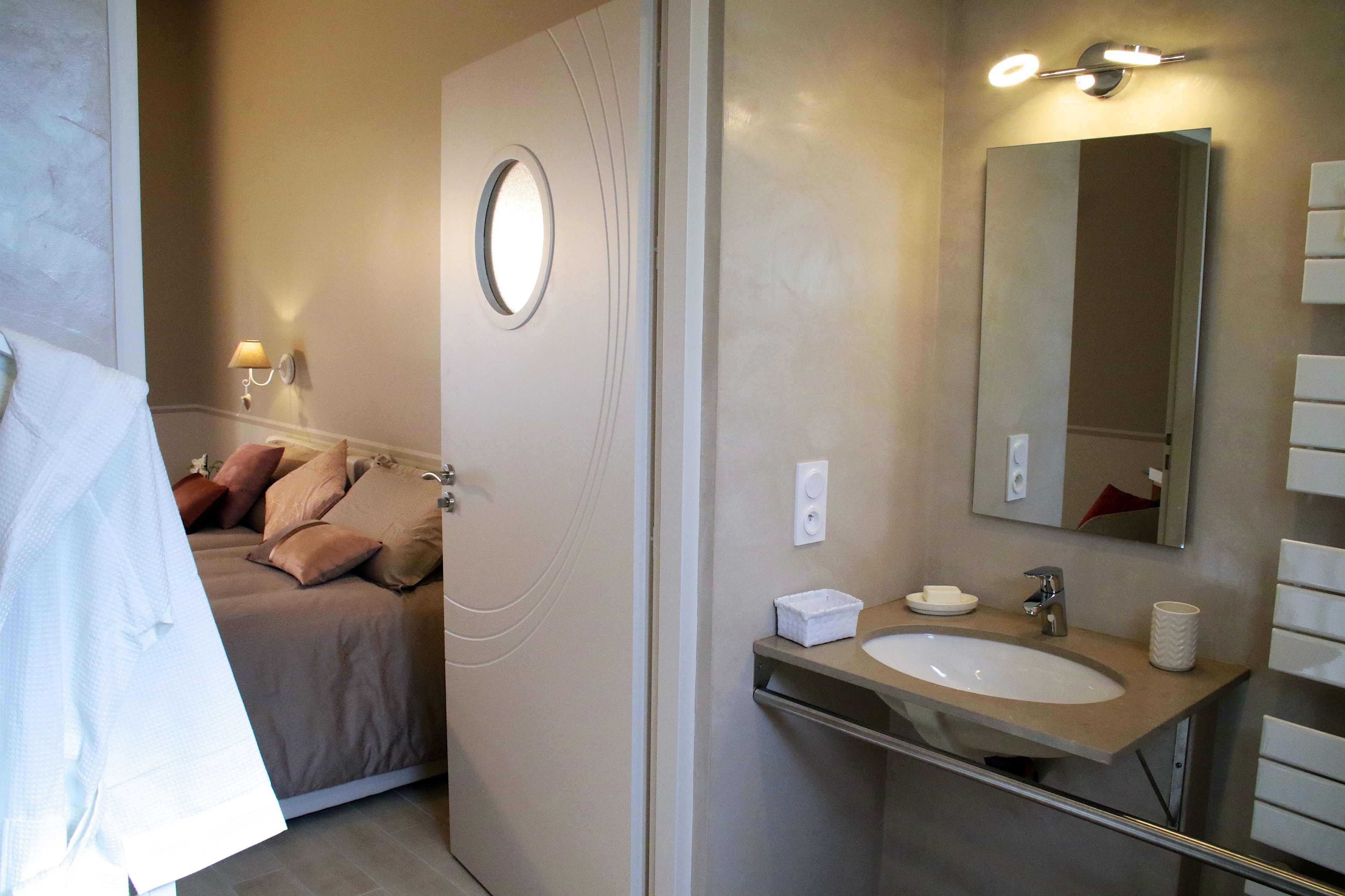 Une salle de bain avec un lit, un lavabo et un miroir.